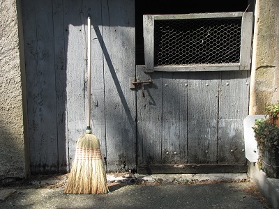 Balai de paille adossé à une porte.
