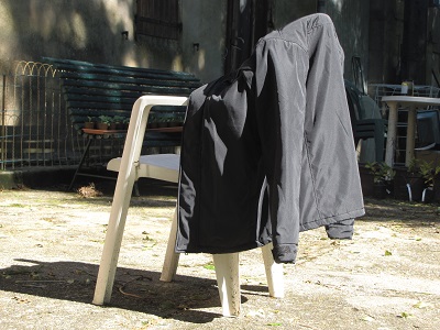 Veste-anorak sur un dossier de chaise d'extérieur.